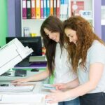two female students using a printer photocopier