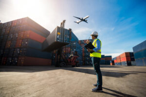 transport worker yellow vest shipping containers airplane blue sky