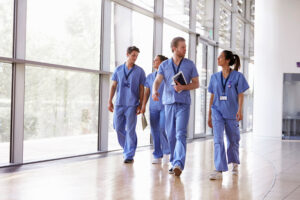 nhs healthcare workers walking in front of glass window hall