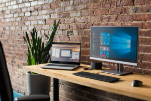 hp laptop monitor on wood desk in front of brick wall