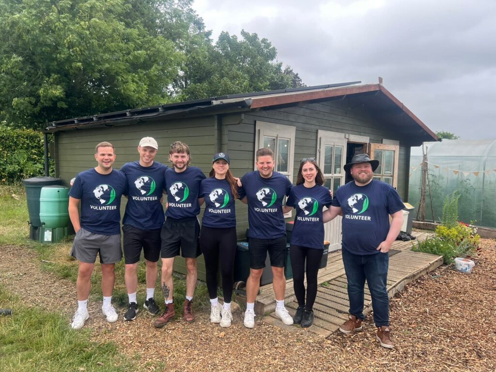 marketing team volunteering at charity Communigrow, standing in front of newly painted central base of operations