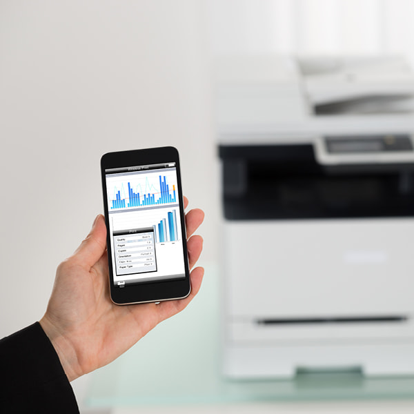 hand holding smartphone interacting with office photocopier printer