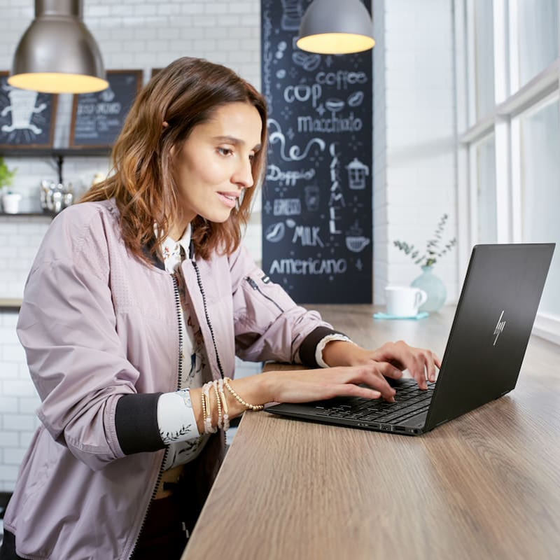 woman in coffee shop working on HP laptop