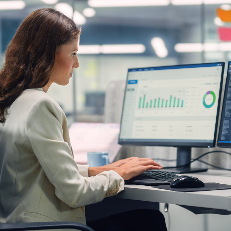 woman on work computer dual monitors graphs