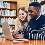 students in a library working on a laptop