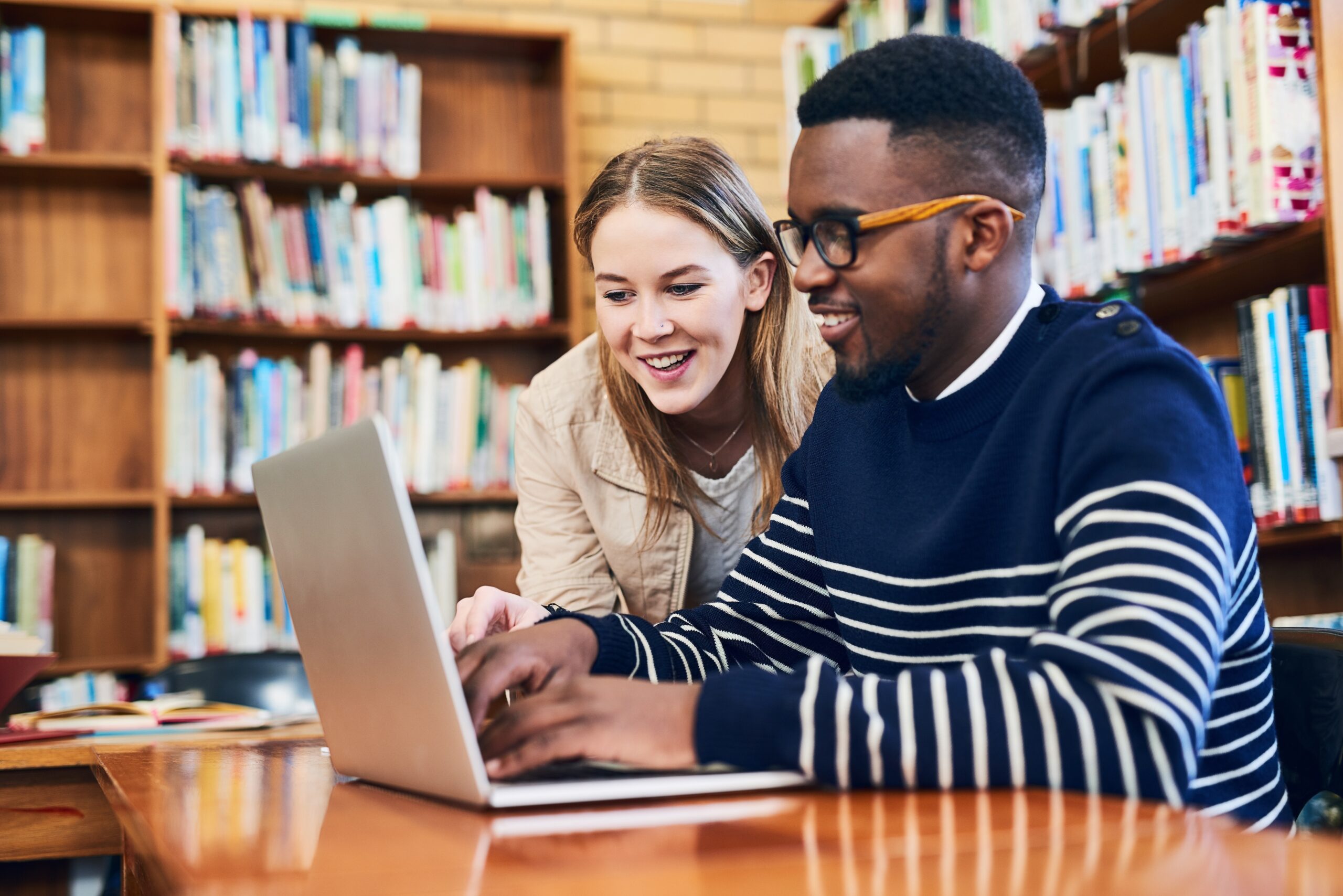 students in a library working on a laptop